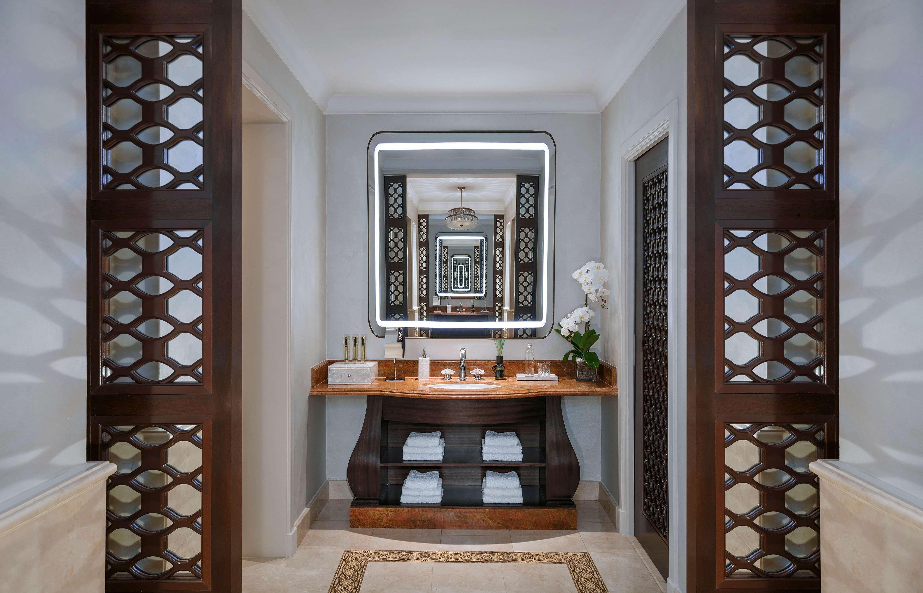 Atlantis, The Palm Dubai Exterior foto The photo shows a stylish bathroom with a modern design. In the center, there is a wooden vanity with a sink, flanked by neatly stacked white towels. Above the vanity is a large, illuminated mirror that enhances the space. To the sides, intricate woo