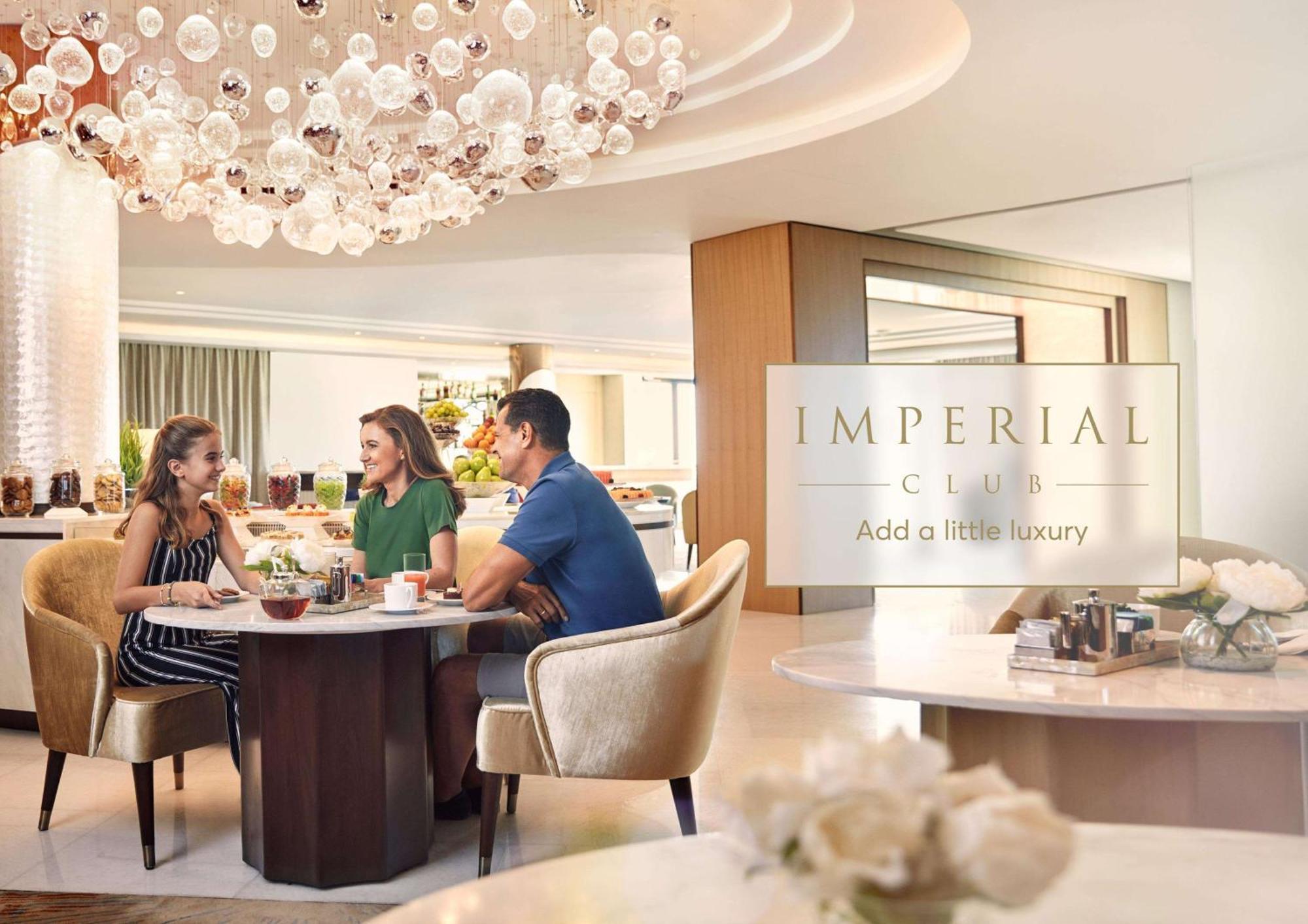 Atlantis, The Palm Dubai Exterior foto The photo shows a luxurious dining setting, likely in a restaurant or cafe. There are three people seated at a circular table, engaged in conversation. Two women and a man are enjoying drinks and possibly light snacks. The interior features elegant d