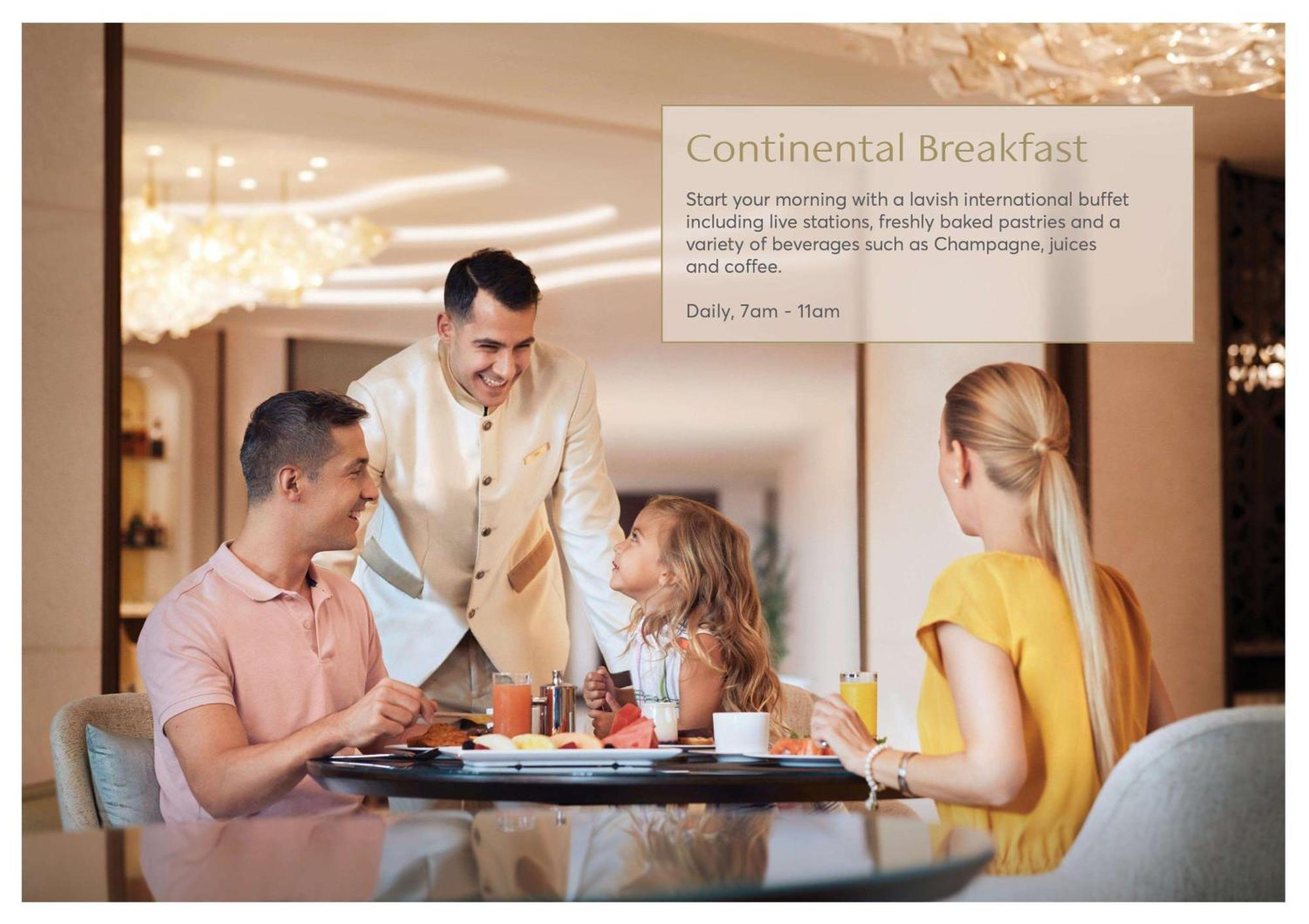 Atlantis, The Palm Dubai Exterior foto The photo depicts a warm and inviting breakfast scene in a dining area. A smiling male server, dressed in a formal outfit, is interacting with a family seated at a table. The family consists of two adults and a young girl. They appear to be enjoying 